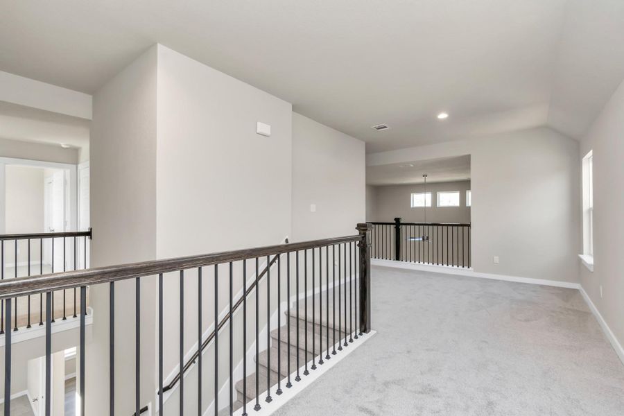 Ascend to the openness: The modern and dark rail stains, coupled with sleek metal balusters, infuse this loft area with a spacious and contemporary ambiance. Sample photo of completed home with similar floor plan. Actual colors and selections may vary.