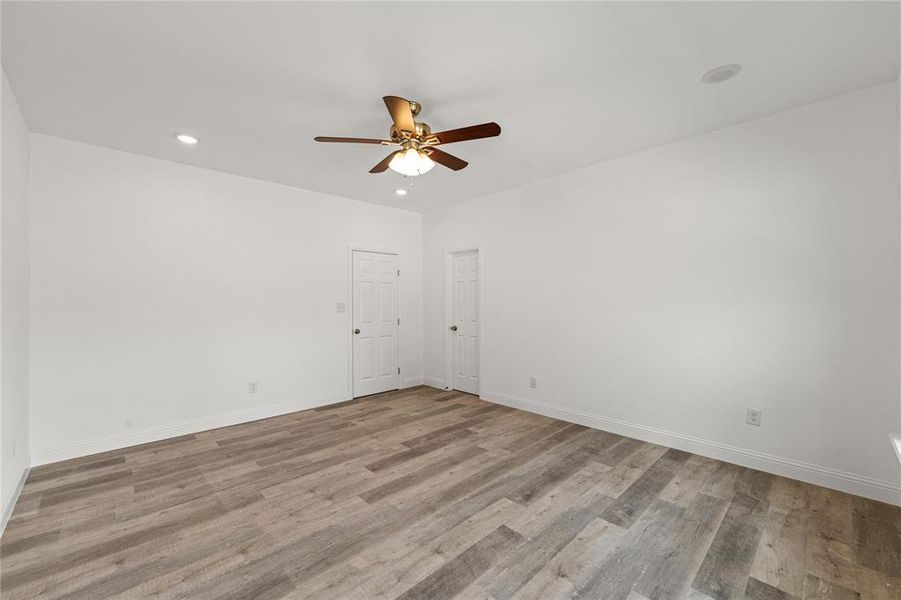 Empty room with ceiling fan and light hardwood / wood-style floors