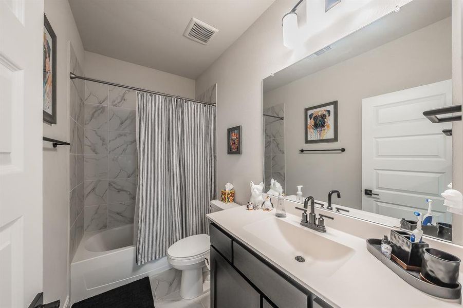 Full bathroom featuring shower / tub combo with curtain, vanity, and light marble finish floors