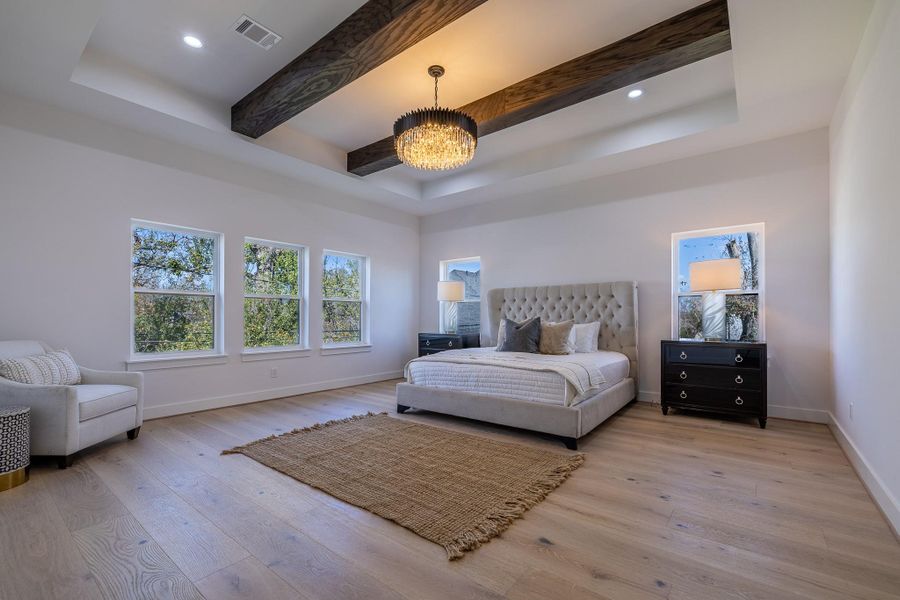 Spacious primary retreat with beam-accented ceiling, abundant natural light, and a serene, private ambiance.