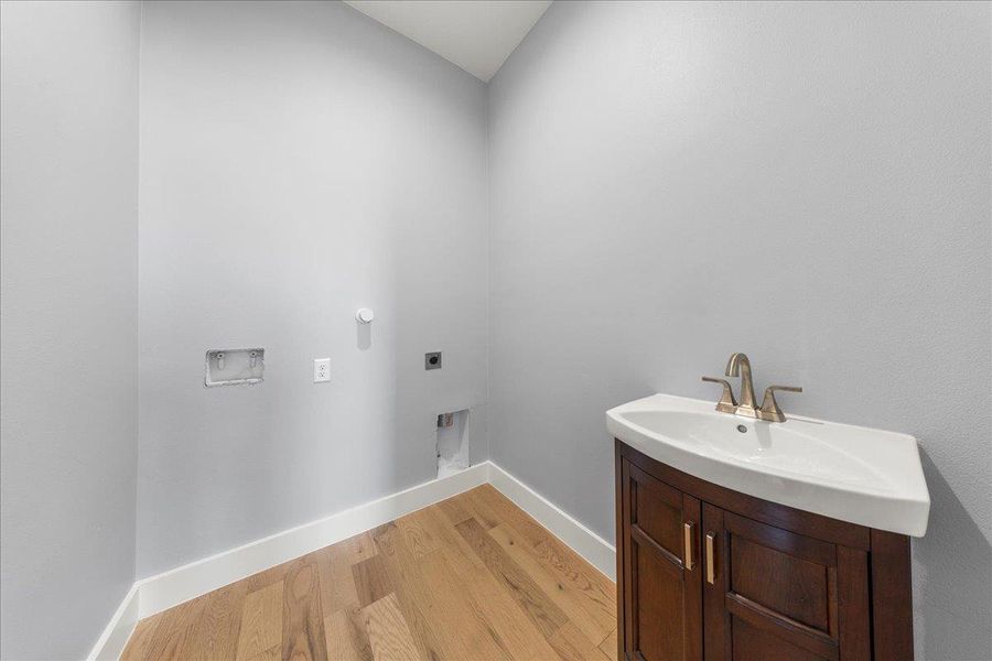 Washroom with light wood finished floors, electric dryer hookup, and hookup for a washing machine Washroom with light wood finished floors, electric dryer hookup, and hookup for a washing machine