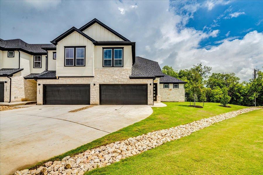 Modern townhome boasts clean lines, durable stone accents, and a verdant lawn.