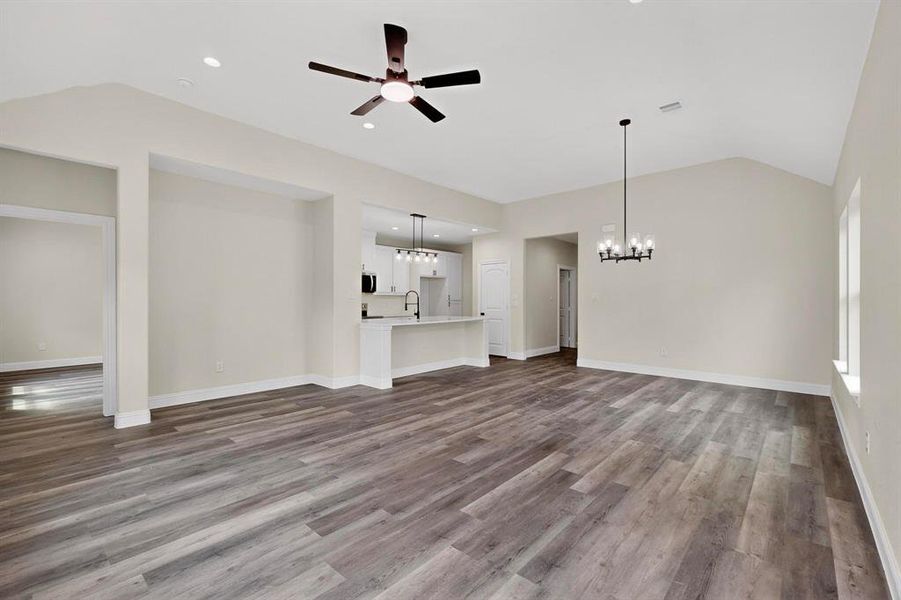 Unfurnished living room featuring dark wood-type flooring, ceiling fan, a chandelier, and recessed lighting Unfurnished living room featuring dark wood-type flooring, ceiling fan, a chandelier, and recessed lighting