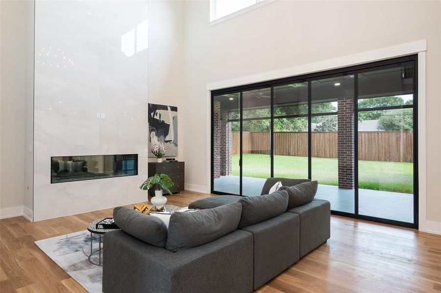 Living room featuring light wood-type flooring, a towering ceiling, and a fireplace