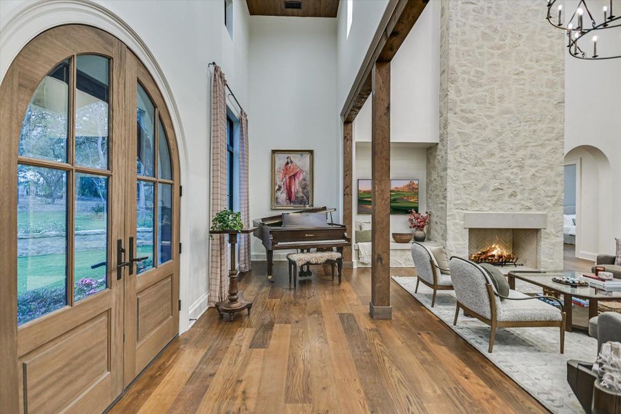 Foyer featuring french doors, hardwood / wood-style flooring, arched walkways, a fireplace, and a high ceiling Foyer featuring french doors, hardwood / wood-style flooring, arched walkways, a fireplace, and a high ceiling