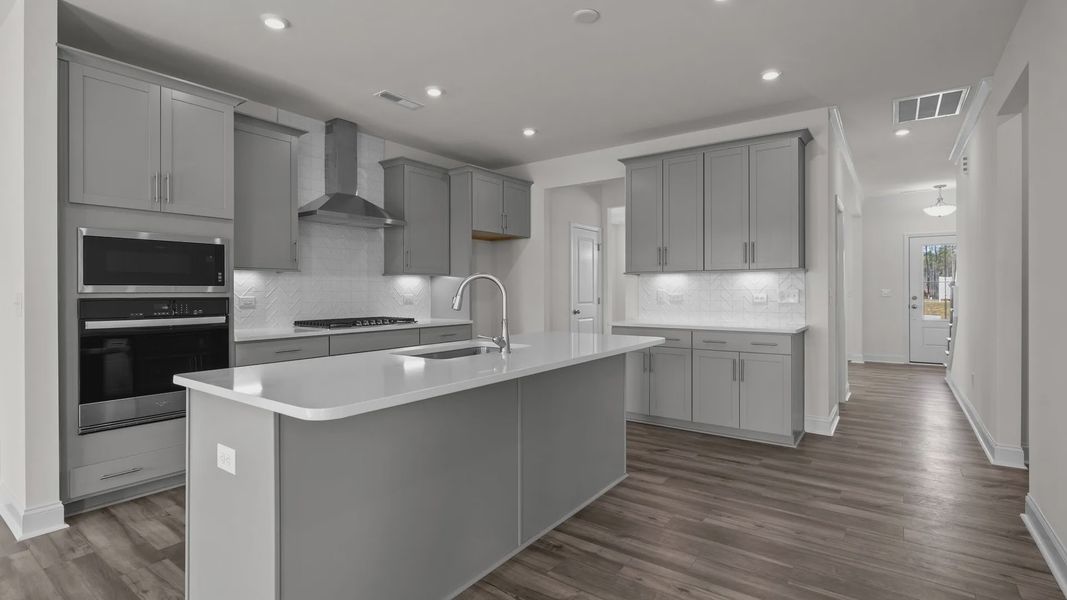 Fairfield design gourmet kitchen with wall oven & microwave, vented hood, and island at Lakeside Glen by DRB Homes, York, SC.