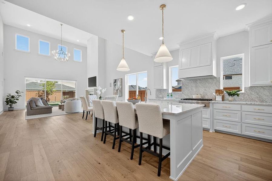 Kitchen with white cabinets, hanging light fixtures, tasteful backsplash, a kitchen bar, and recessed lighting Kitchen with white cabinets, hanging light fixtures, tasteful backsplash, a kitchen bar, and recessed lighting