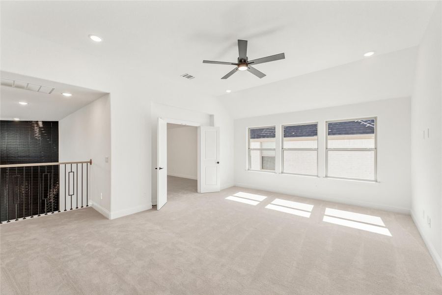 Spacious upstairs bonus room with carpet, ceiling fan, and staircase railing visible in corner