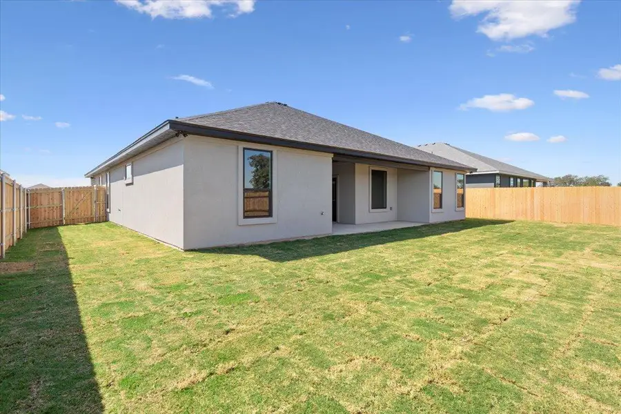 Back of property with a fenced backyard, a patio, and stucco siding