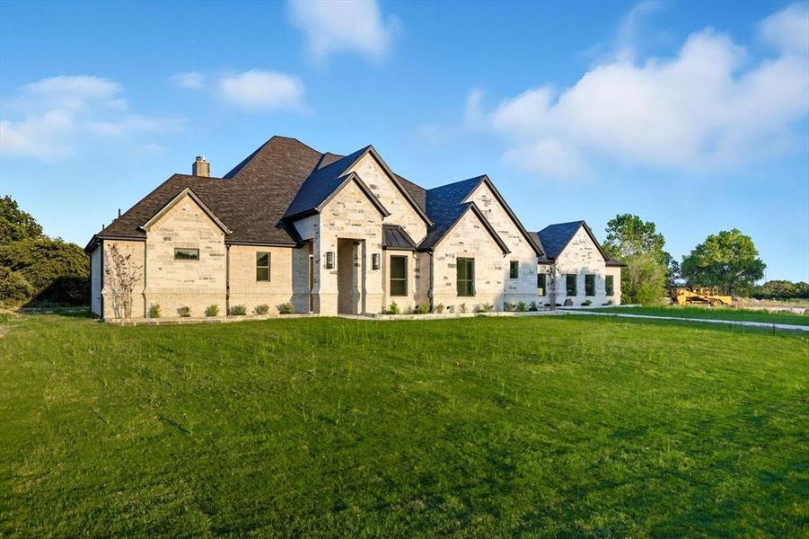 French country inspired facade with a front yard, a chimney, and brick siding French country inspired facade with a front yard, a chimney, and brick siding