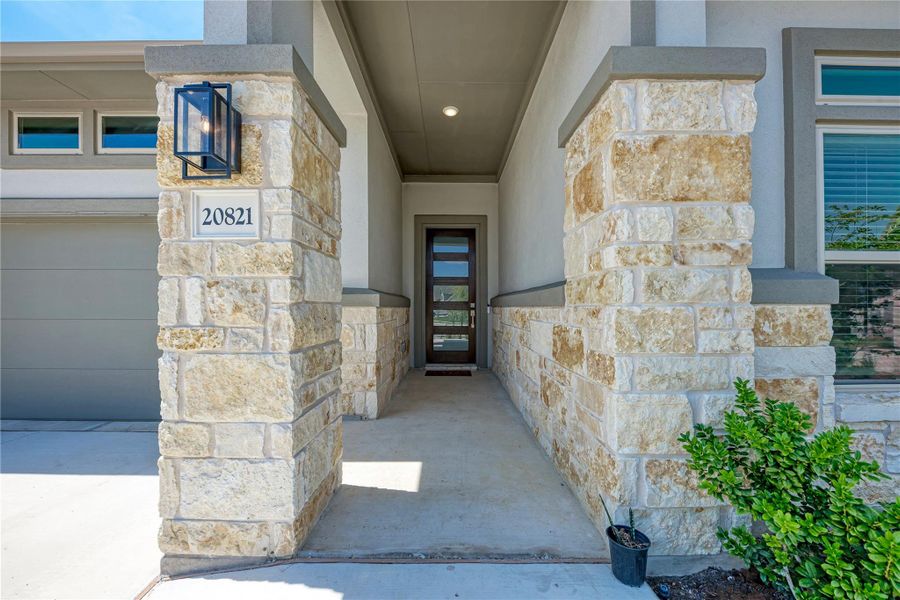 A welcoming front entry features stone columns and a modern door with horizontal lites.