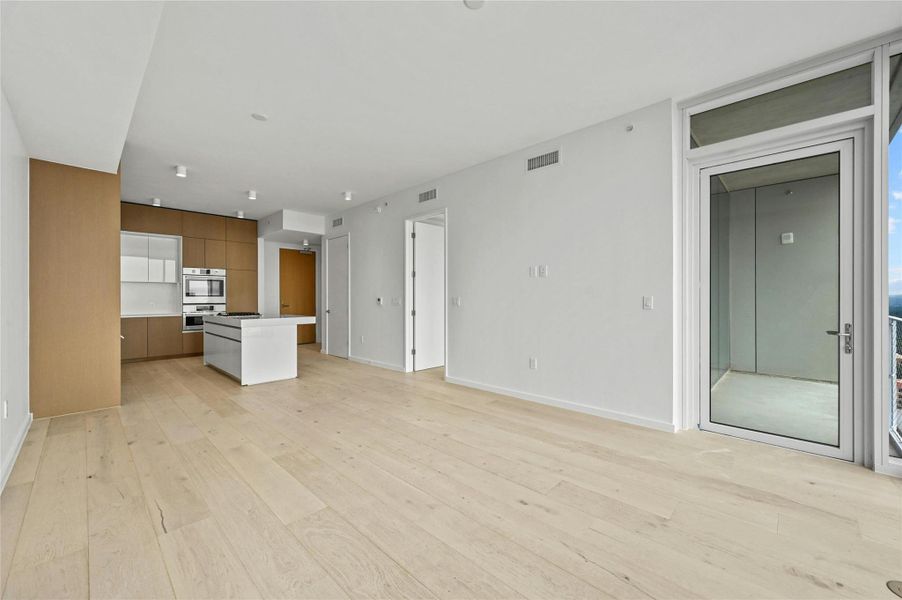 Open-concept living and dining anchored by a sleek Rhode Partners–designed kitchen with Silestone® island, integrated Bosch® appliances, and custom cabinetry. Wide-plank oak floors carry throughout, and sliding glass doors extend the living space onto a private balcony for indoor-outdoor enjoyment. Open-concept living and dining anchored by a sleek Rhode Partners–designed kitchen with Silestone® island, integrated Bosch® appliances, and custom cabinetry. Wide-plank oak floors carry throughout, and sliding glass doors extend the living space onto a private balcony for indoor-outdoor enjoyment.