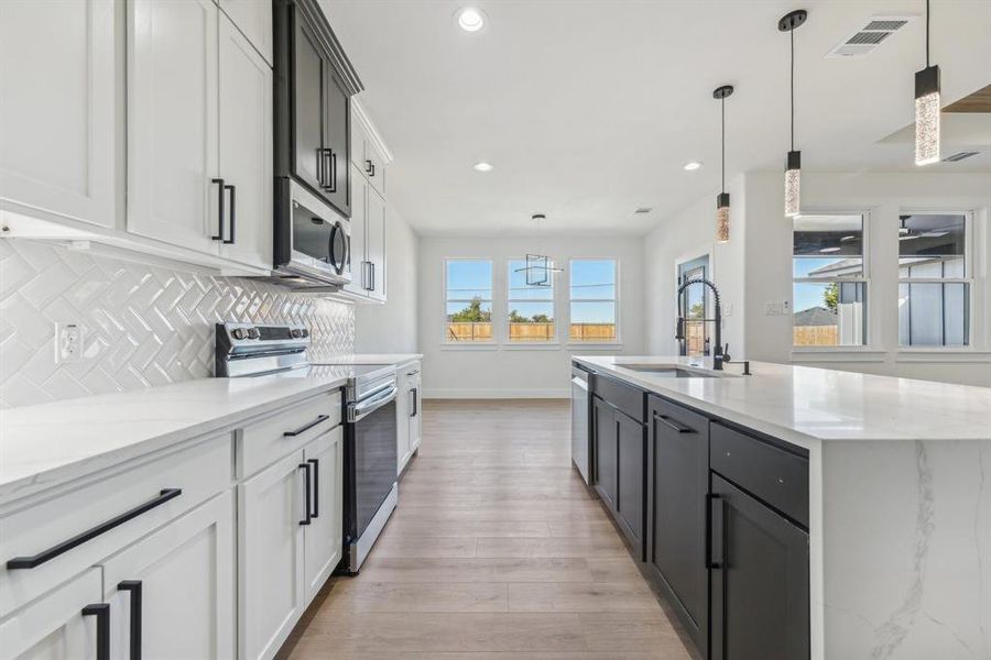 Kitchen featuring appliances with stainless steel finishes, decorative light fixtures, a wealth of natural light, and sink