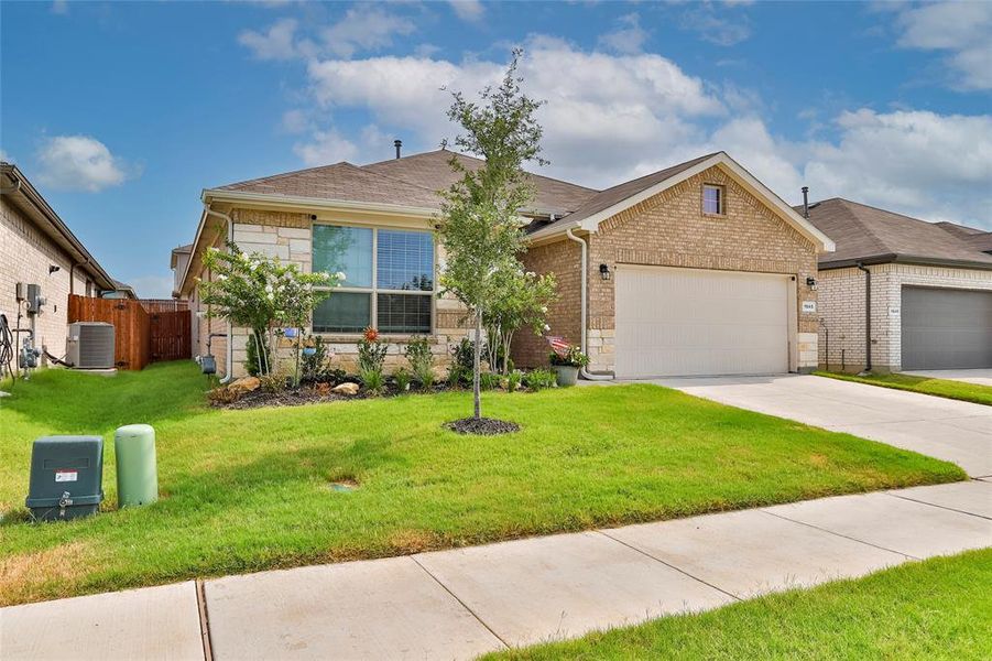 Single story home featuring driveway, a garage, brick siding, and stone siding Single story home featuring driveway, a garage, brick siding, and stone siding