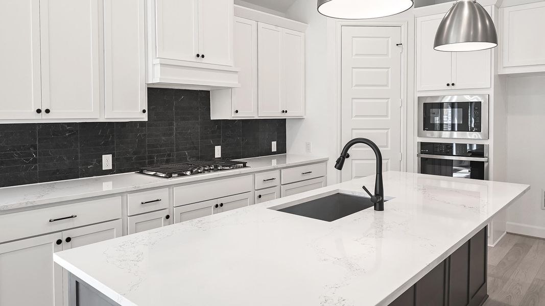 Kitchen with backsplash, white cabinets, appliances with stainless steel finishes, and light stone counters Kitchen with backsplash, white cabinets, appliances with stainless steel finishes, and light stone counters