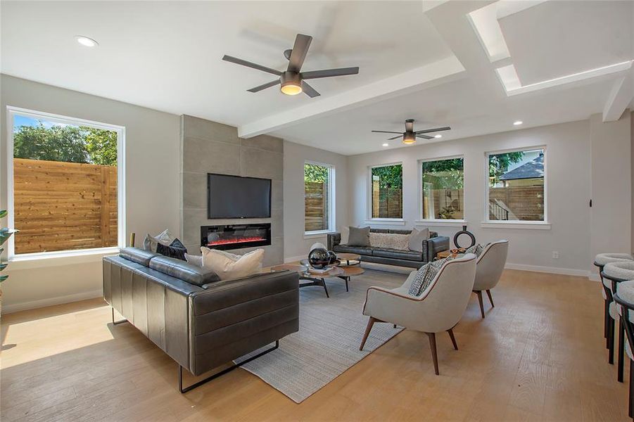 Living room featuring beam ceiling, light hardwood / wood-style flooring, a fireplace, and ceiling fan