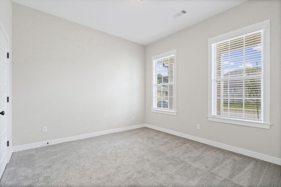 Neutral-toned room featuring two windows with white blinds, light gray wall paint, gray carpet flooring, and white trim Neutral-toned room featuring two windows with white blinds, light gray wall paint, gray carpet flooring, and white trim