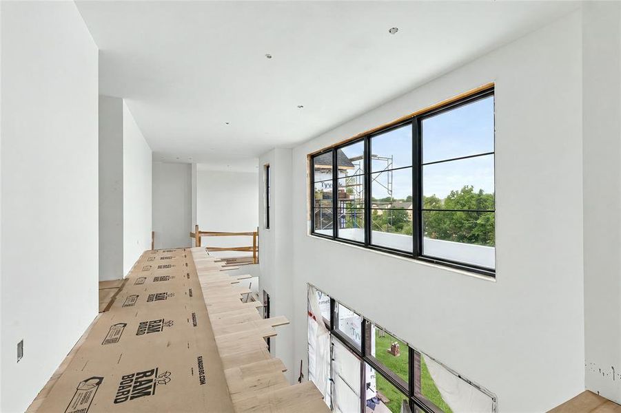 Expansive interior featuring an upper-level hallway, high ceilings, and recessed lighting