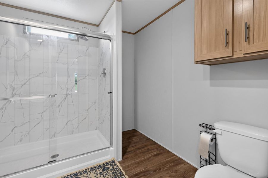 A well-appointed bathroom features a spacious glass-enclosed shower alongside modern wood-look flooring.