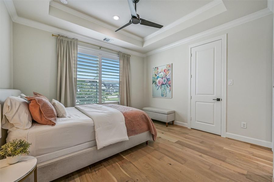 Privately positioned at the front of the home just off the foyer, the first-floor guest suite features wood flooring, a tray ceiling with crown molding, plantation shutters and its own private en-suite bath.