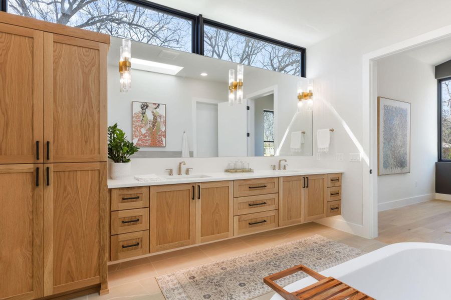 Full bathroom featuring tile patterned flooring, double vanity, a skylight, and a sink