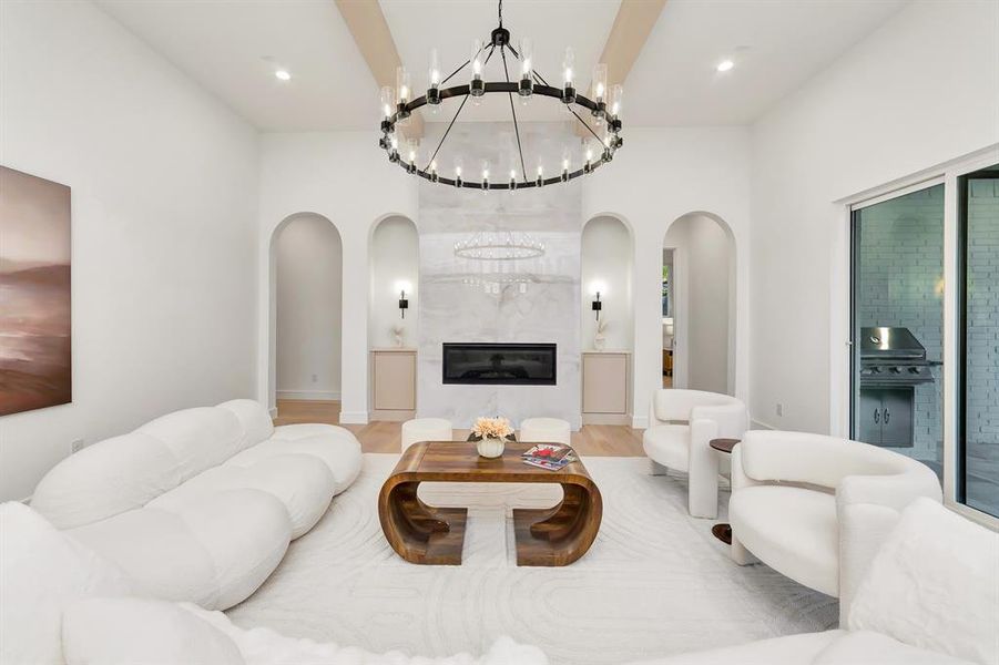 Living area featuring a fireplace, arched walkways, wood finished floors, and a chandelier Living area featuring a fireplace, arched walkways, wood finished floors, and a chandelier