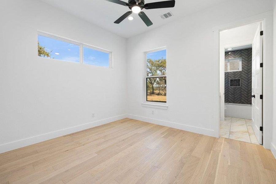 Unfurnished bedroom with light wood-type flooring, a ceiling fan, ensuite bathroom, and recessed lighting