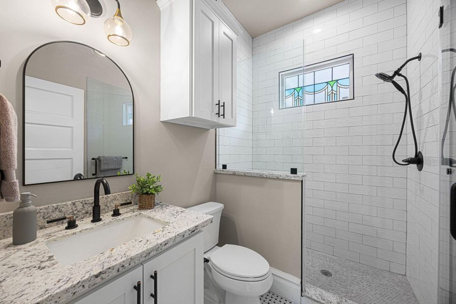 En-suite bathroom for the 1st floor bedroom, with a nicely appointed walk-in shower with frameless glass surround, accent window, and timeless subway tile run to the ceiling. En-suite bathroom for the 1st floor bedroom, with a nicely appointed walk-in shower with frameless glass surround, accent window, and timeless subway tile run to the ceiling.