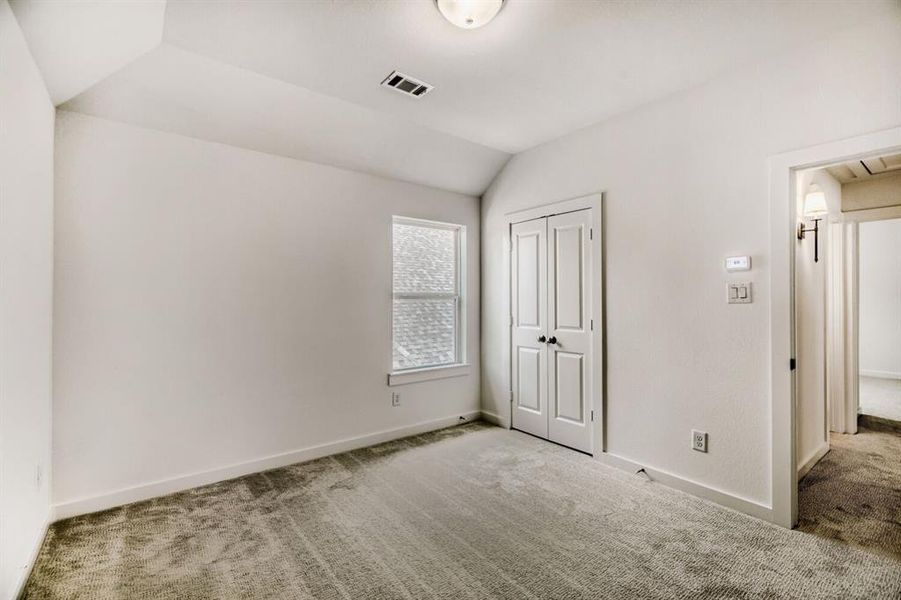 Unfurnished bedroom with carpet flooring, lofted ceiling, and a closet