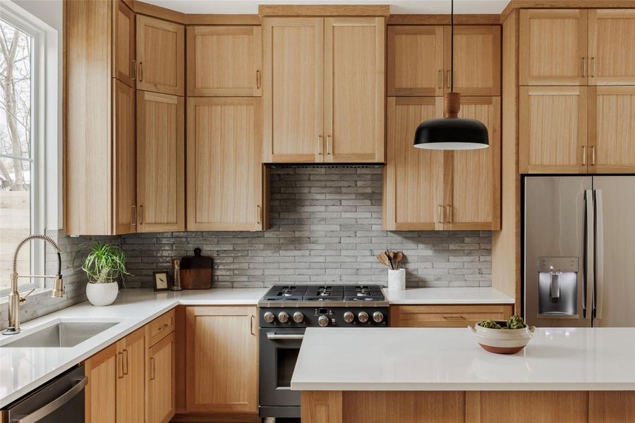 Kitchen with stainless steel appliances, light stone countertops, and light wood finish cabinets