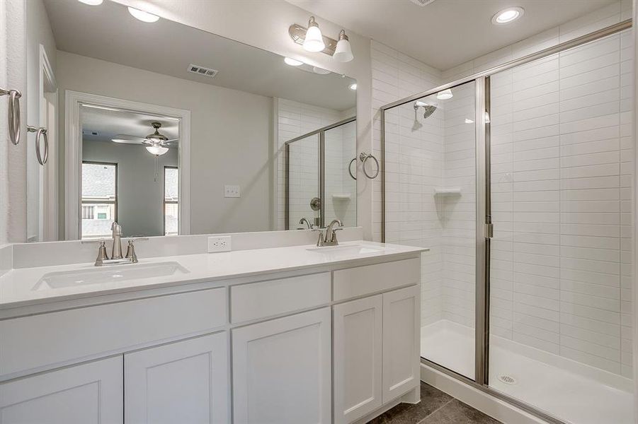Full bathroom with double vanity, a shower stall, a ceiling fan, and recessed lighting