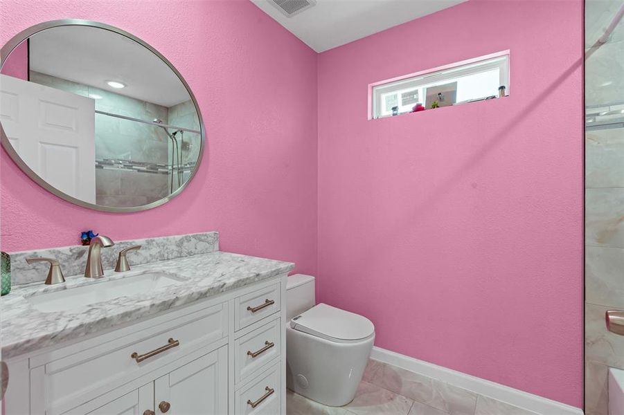 Bathroom featuring a tile shower, vanity, and a textured wall Bathroom featuring a tile shower, vanity, and a textured wall