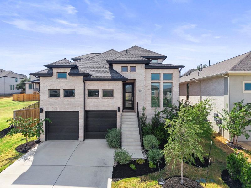 Multi-level modern design pairs light brickwork with a dark roofline and prominent windows.