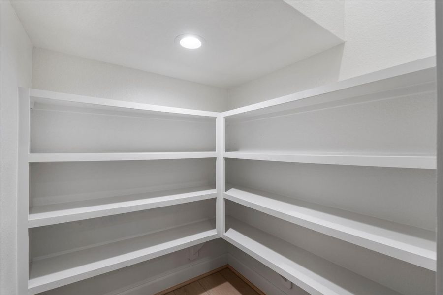 Spacious walk-in pantry with custom built-in shelving and recessed lighting. Spacious walk-in pantry with custom built-in shelving and recessed lighting.