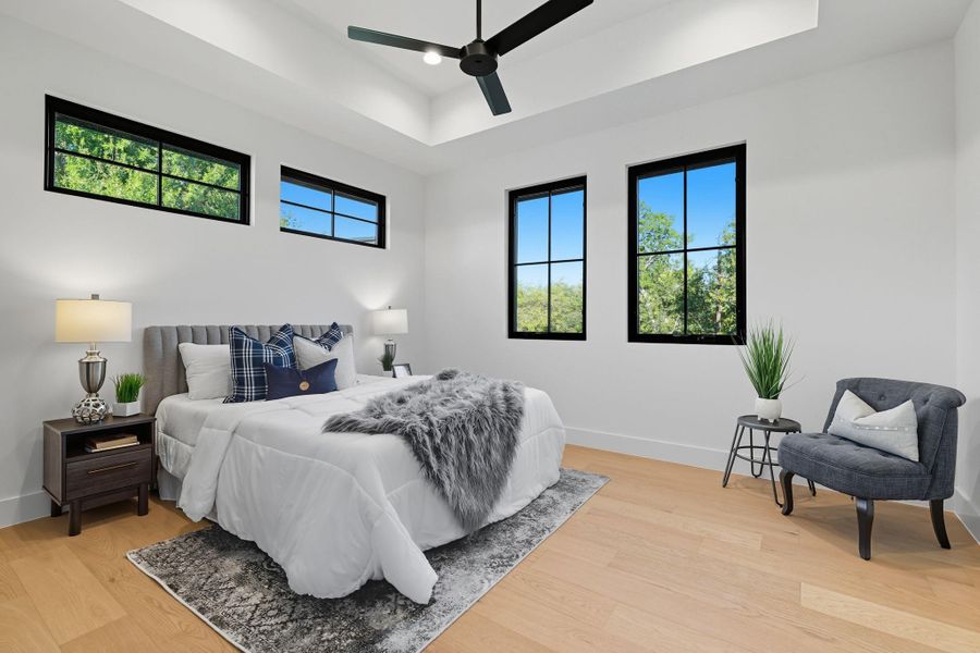 Bedroom featuring a tray ceiling, light wood-style floors, and a ceiling fan Bedroom featuring a tray ceiling, light wood-style floors, and a ceiling fan