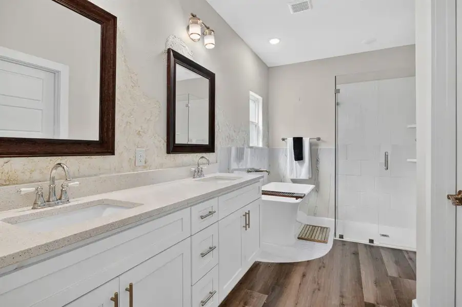 Double vanity sinks, faux finish painting behind the custom mirrors, seperate Hollywood soaking bathtub with custom tile underneath the tub, and custom glass shower with tile designs.
