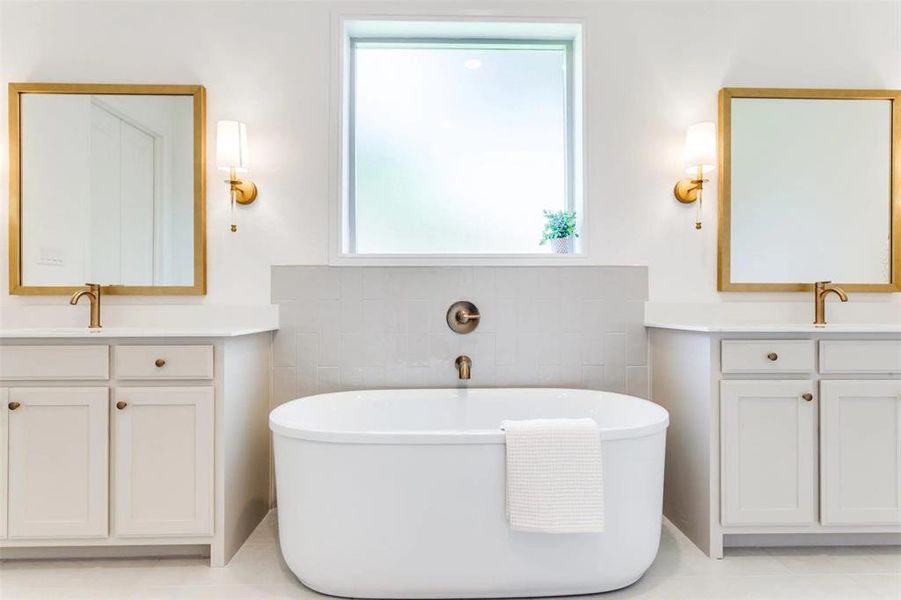 Bathroom with a soaking tub, two vanities, and light tile patterned flooring