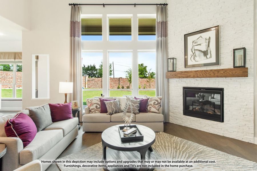Living room with white brick fireplace, tall windows, gray sofas, and hardwood floors