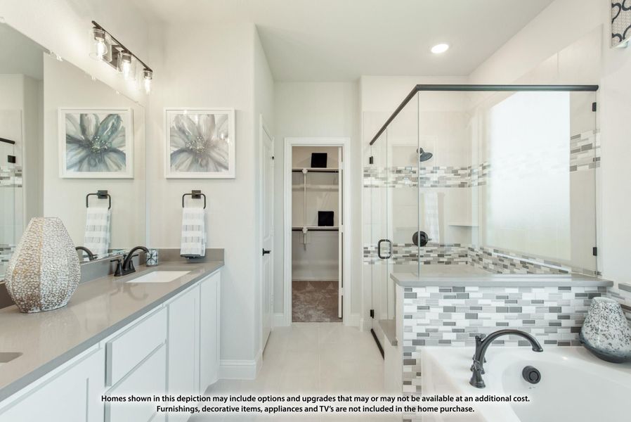 Master bathroom with double vanity, glass walk-in shower, soaking tub, and walk-in closet entry
