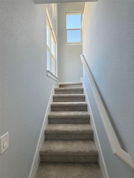 The staircase to the second floor is conveniently illuminated by natural light, thanks to multiple windows.