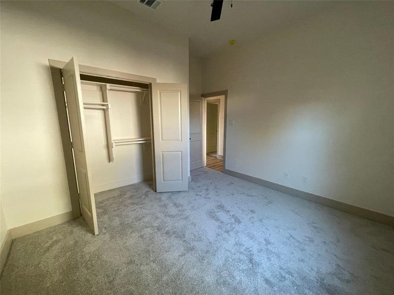 Secondary bedroom with light carpet, a closet, and ceiling fan