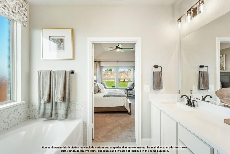 Ensuite bathroom with soaking tub, double vanity, and open view into master bedroom with ceiling fan Ensuite bathroom with soaking tub, double vanity, and open view into master bedroom with ceiling fan