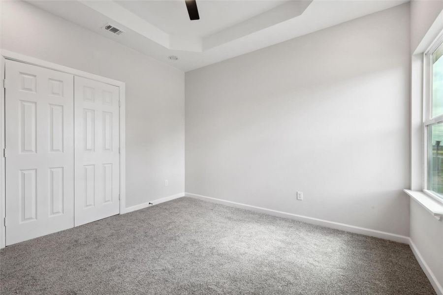 Unfurnished bedroom featuring carpet floors, a tray ceiling, a closet, and baseboards Unfurnished bedroom featuring carpet floors, a tray ceiling, a closet, and baseboards