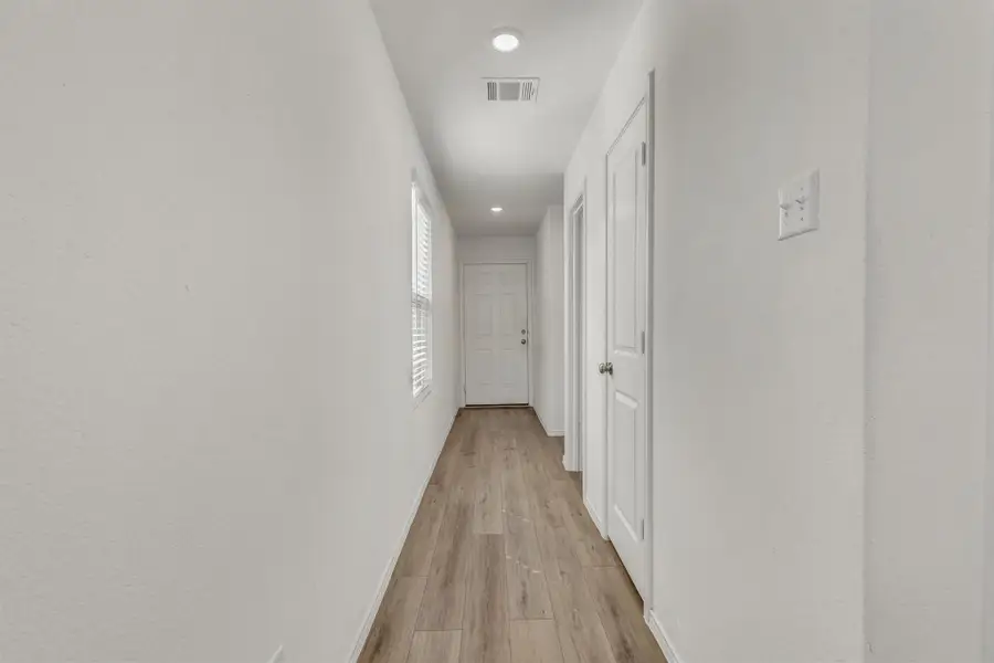Smooth wood-look flooring guides the way down a long hallway featuring recessed lighting. Smooth wood-look flooring guides the way down a long hallway featuring recessed lighting.