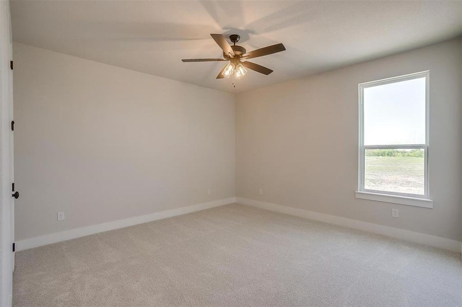 Unfurnished room with light colored carpet, ceiling fan, and baseboards Unfurnished room with light colored carpet, ceiling fan, and baseboards