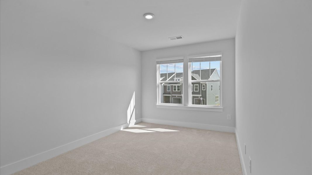 Elegant carpeted bedroom with walk-in closet and wall-to-wall windows offering natural brightness Elegant carpeted bedroom with walk-in closet and wall-to-wall windows offering natural brightness