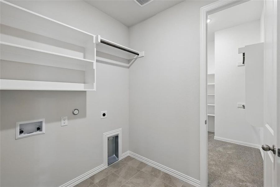 Laundry area featuring hookup for a gas dryer, hookup for an electric dryer, washer hookup, light colored carpet, and light tile patterned flooring Laundry area featuring hookup for a gas dryer, hookup for an electric dryer, washer hookup, light colored carpet, and light tile patterned flooring