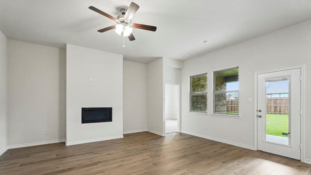 Living area featuring wood-finish flooring, a contemporary fireplace, and a ceiling fan with integrated lighting