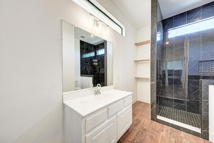 High ceilings and a dark-tiled walk-in shower elevate this modern bathroom design.