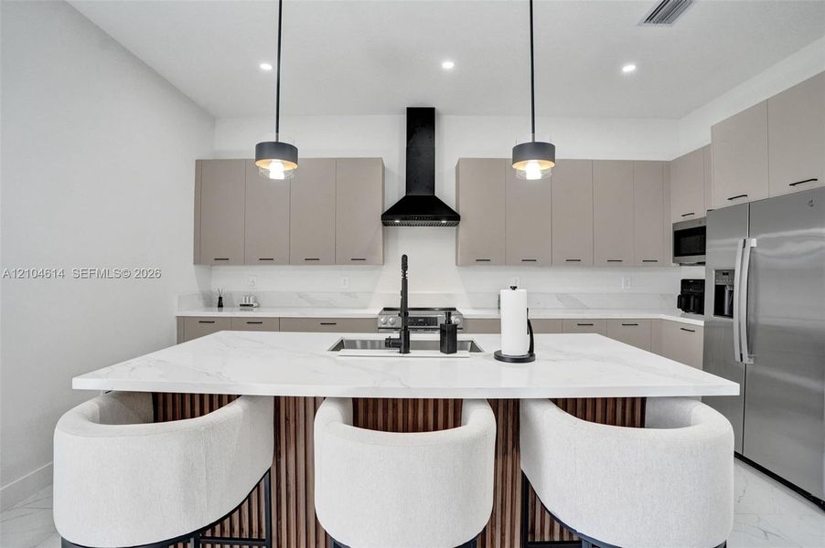 Kitchen featuring a large island with white countertop, integrated sink, and wood-slat detailing